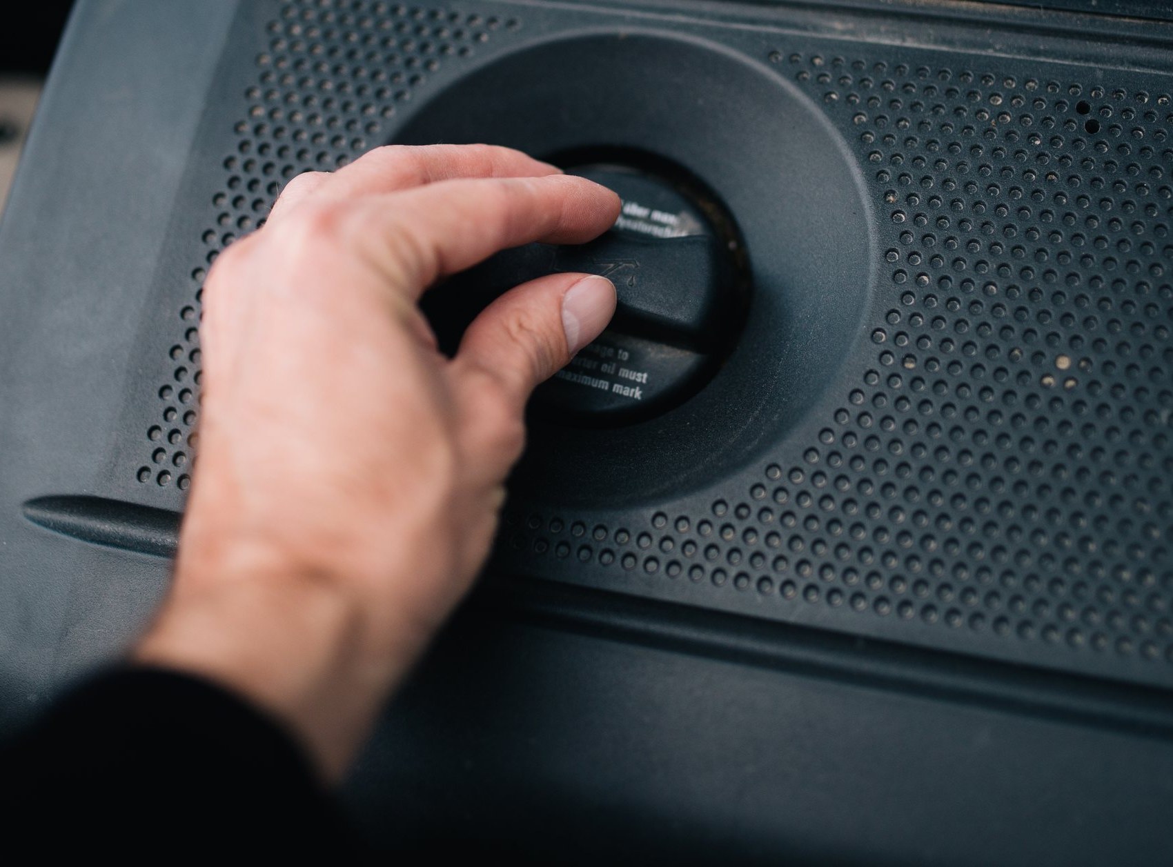 Hand draait de olievuldop van een motor open